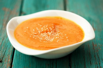 Homemade pumpkin soup puree with sesame seeds in white bowl on t