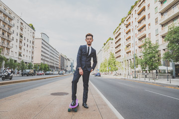 Young handsome Asian model posing with his skateboard