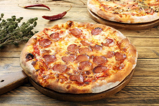 pizza con salame piccante sfondo legno rustico