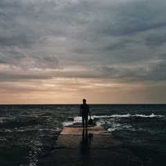 Man with bag in a hand stands on a pier.