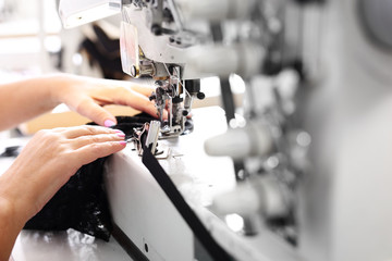 Produkcja odzieży.Szwaczka szyje na maszynie do szycia w zakładzie produkcyjnym - obrazy, fototapety, plakaty