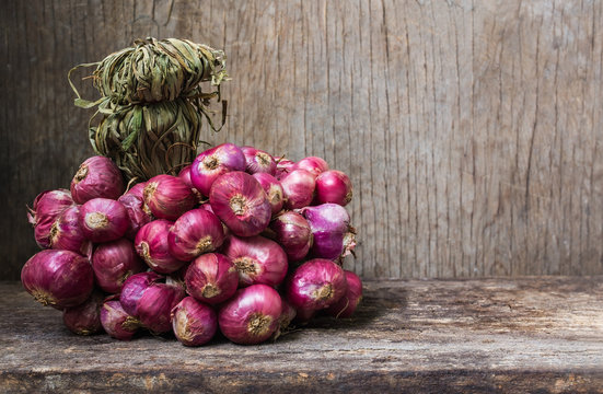 Bunch of fresh red onions on old wooden background