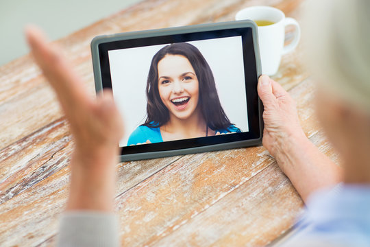 senior woman with photo on tablet pc at home