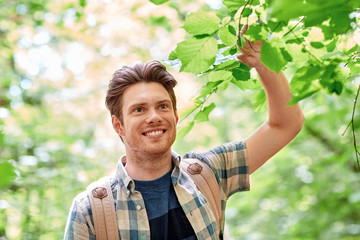 Naklejka na ściany i meble smiling young man with backpack hiking in woods