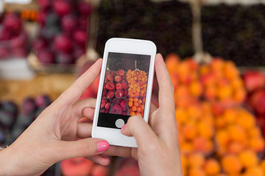 hands with smartphone taking picture of fruits