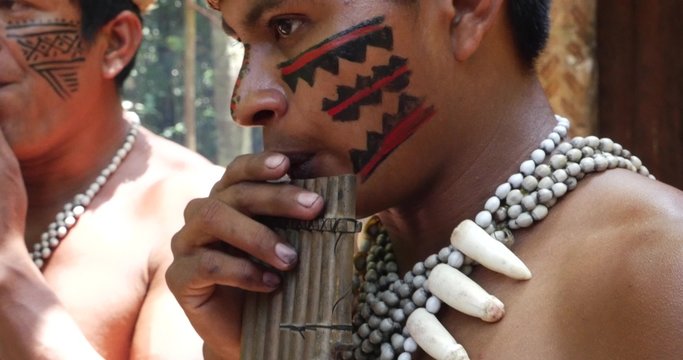 Native Brazilian playing wooden flute at an indigenous tribe in the Amazon