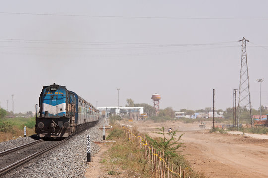 Fototapeta An express passenger train passing through rural Rajasthan near Pali. India has a vast rail network