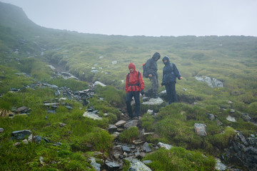 Fototapeta na wymiar Hikers in raincoats on mountain