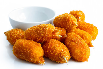 Pile of fried breaded surimi crab claws with empty dip bowl isol