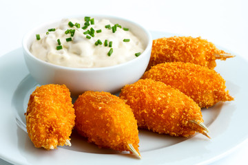 Plate of fried breaded surimi crab claws with bowl of tartar sau