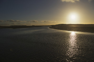 Fototapeta premium Sunset at Cadzand Belgium showing river flowing in north sea at sunset