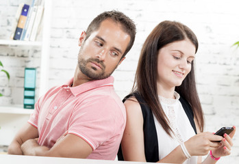 Obraz premium young couple sitting back to back, woman phone