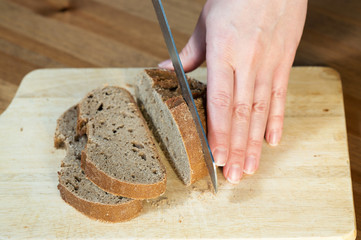 Hands cutting rye bread. Shallow dof.