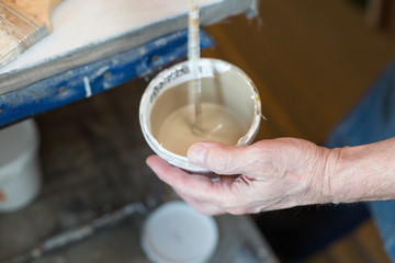 An artist preparing primer for canvas