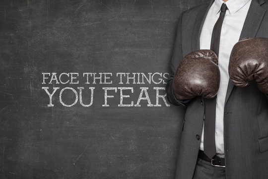 Face the things you fear on blackboard with businessman on side