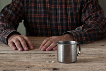 Fototapeta na wymiar Empty steel cup bread crumbs on a wooden table closeup