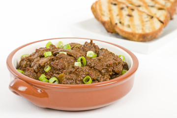 Higados de Pollo - Chicken livers with chorizo & spring onions finished with a dark Cajun tomato sauce. Served with garlic bread.
