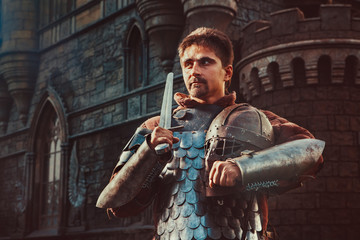 Medieval knight with the sword on the ancient castle background