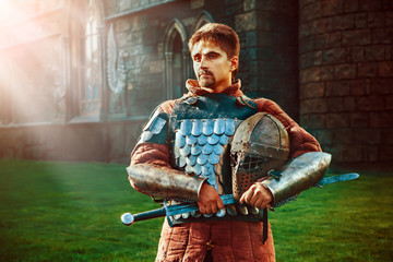 Medieval knight with the sword on the ancient castle background