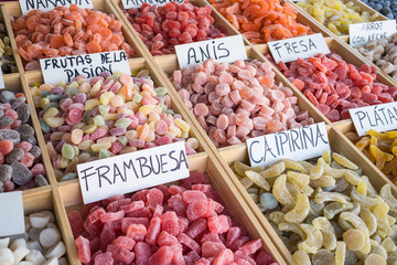 Sugar coated fruit gums on display in Spain. The  hand written labels read as follows: Orange, Blueberry, Passion fruits, aniseed, strawberry, rice with milk, rasberry, Caipirina, Banana,
