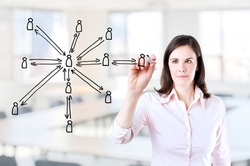 Young business woman drawing social network structure. Office background. 