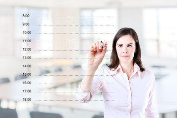 Young business woman writing blank appointment schedule. Office background.