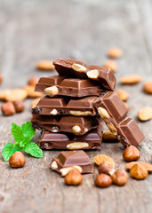 Pile of chocolate slices with mint and nuts on an old wooden tab