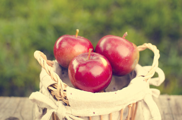 Detail of three apples in a basket and green background