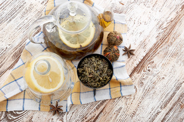 Ripe lemon, cinnamon and fruit drink in glass teapot on wooden