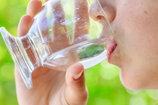 closeup of a healthy young girl drinking glass of water outdoors
