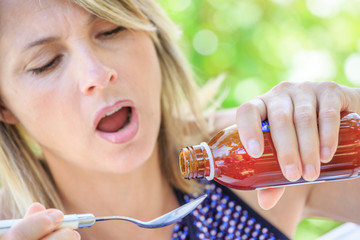 closeup of pretty woman taking a syrup on a spoon