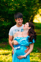 Fototapeta premium Beautiful pregnant couple relaxing outside in the park.