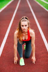 Athletic woman on track starting to run. Healthy fitness concept