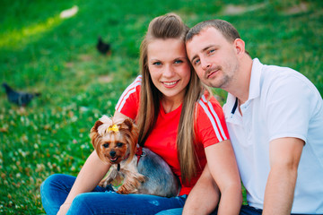 Happy young couple in love with dog. Park outdoors.