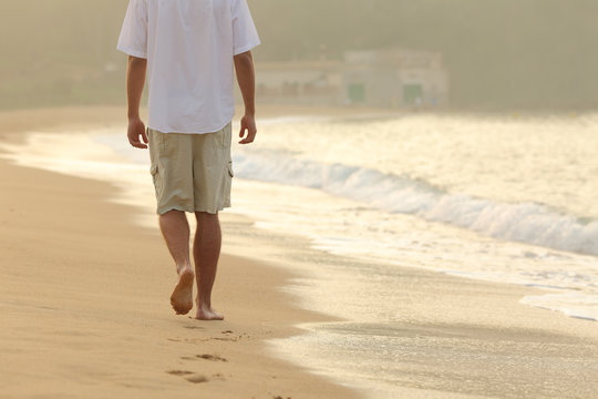 Man walking and leaving footprints on the sand of a beach