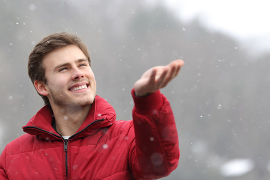 Man watching the snow falling on his hand in winter