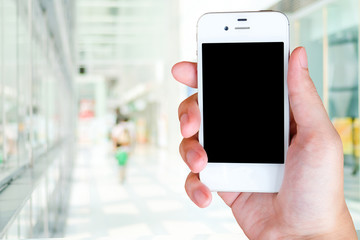Fototapeta na wymiar Hand holding smart phone over blur office building background