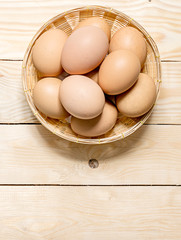 Hen eggs in basket on table