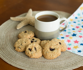 homemade cranberry oatmeal cookies with cup of hot coffee on the wood table and plate mat
