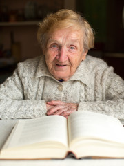 Portrait of Old woman reading a book sitting at the table.