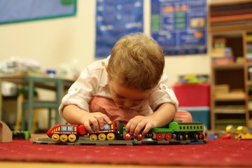 bambino molto concentrato gioca e si diverte a scuola con un trenino giocattolo