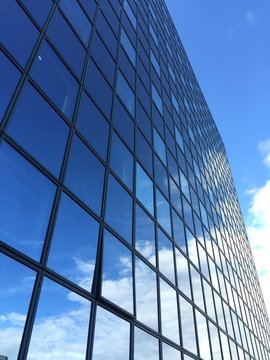 grattacielo di vetro che riflette cielo azzurro e nuvole