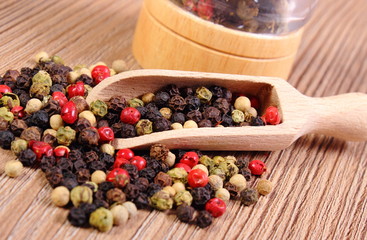 Pepper with spoon and mill on wooden background