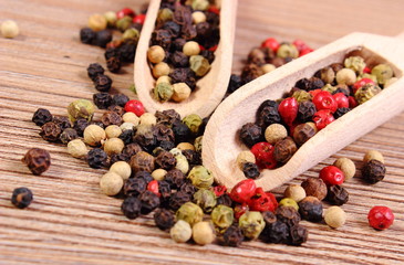 Fresh colored pepper with spoon on wooden background