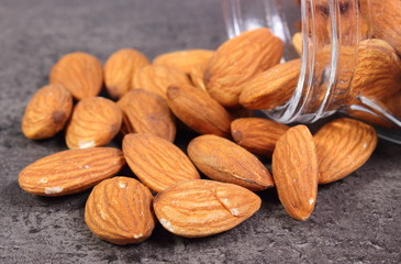 Almonds spilling out of glass jar on concrete structure