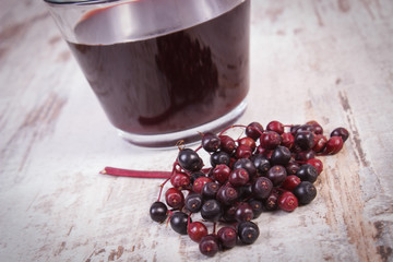 Bunch of fresh elderberry with juice on old wooden background, healthy nutrition