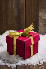Christmas gift box with a gold ribbon bow on snow