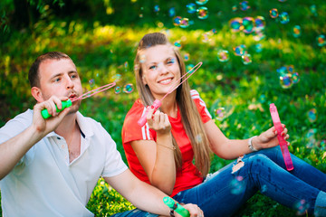 Couple Relaxing in the Park with bubble blower. Spring time