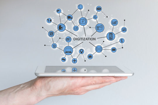 Digitization and digital disruption concept. Male hand holding modern tablet or smart phone with illustration of connected devices and information.