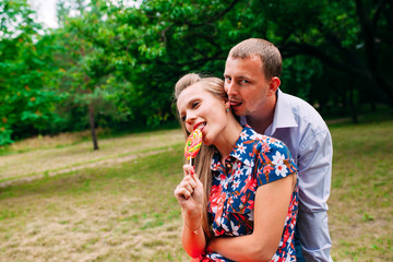 Fototapeta premium Lollipop fun. Young loving couple tasting multi colored lollipop